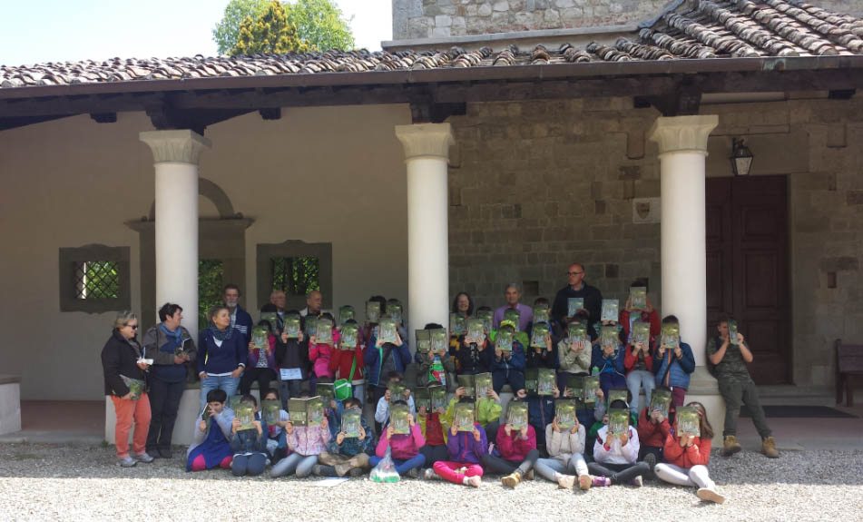 Classi della scuola primaria di Scarperia dopo l'escursione nel bosco mostrano il libro fumetto che accompagna il progetto didattico.